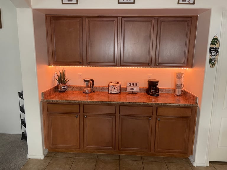 Built-in wooden cabinet with orange backsplash displaying decorative items and coffee-related accessories