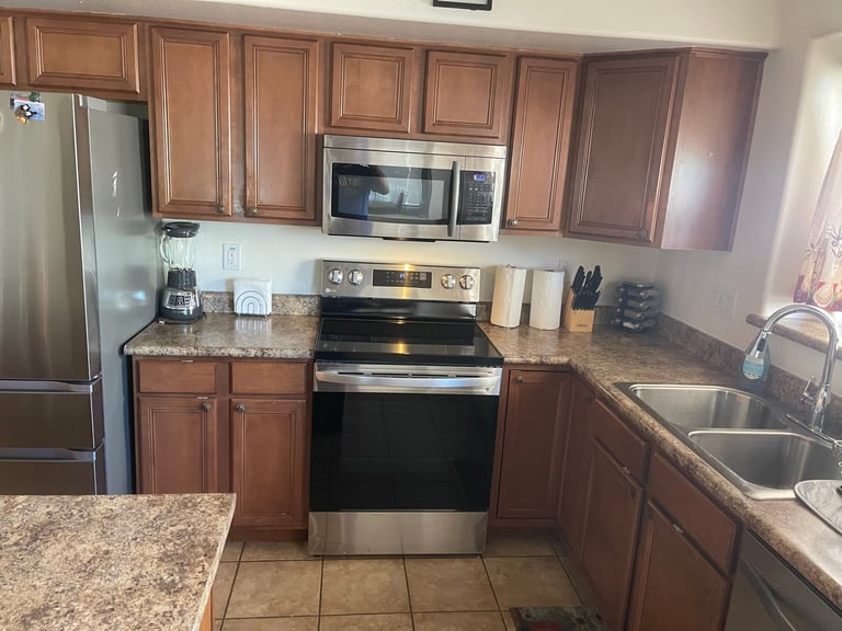 Modern kitchen with wood cabinets, granite countertops, stainless steel appliances, and tile flooring